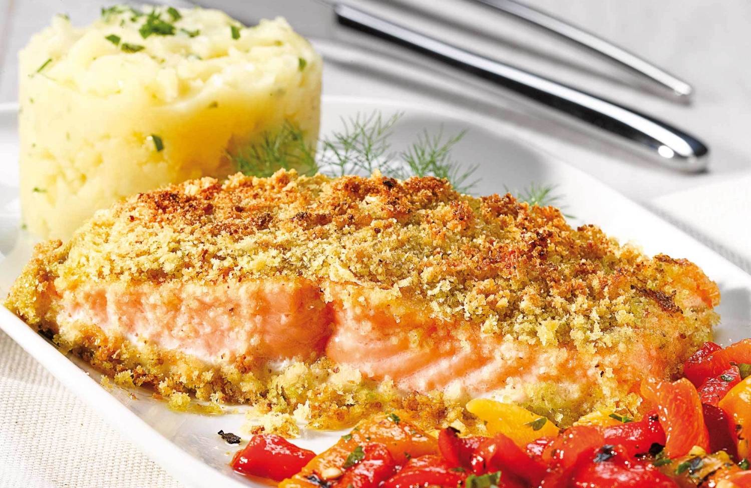 Filete de salmón dorado con pistachos, papas y pimientos asados